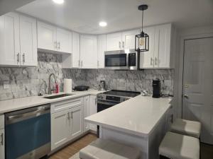 a kitchen with white cabinets and a white counter top at Modern & Cozy Suite in Norwood