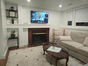 a living room with a couch and a tv above a fireplace at Modern & Cozy Suite in Norwood +4 photos