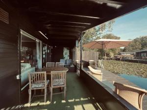 a porch with a table and chairs and an umbrella at Modern waterfront chalet in Geel