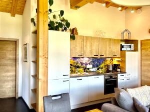 a kitchen with white cabinets and a couch at Traumferienwohnung Alpenliebe Sommer-Hörnerbahnen kostenlos in Bolsterlang