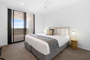 a white bedroom with a large bed and a window at Alcyone at The Corso in Maroochydore +17 photos