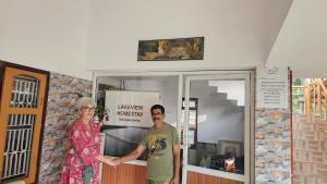 a man and a woman standing in front of a door at lakeview homestay in Trikarpur