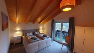 a bedroom with a bed and a large window at Ferienhaus Alpenherz Sommer-Bergbahnen-kostenlos in Bolsterlang