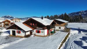 a house covered in snow with mountains in the background at Ferienhaus Alpenherz Sommer-Bergbahnen-kostenlos in Bolsterlang