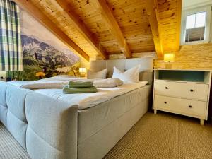 a bedroom with a large bed with a wooden ceiling at Ferienhaus ALPVERLIEBT Sommer-Hörnerbahnen kostenlos in Bolsterlang