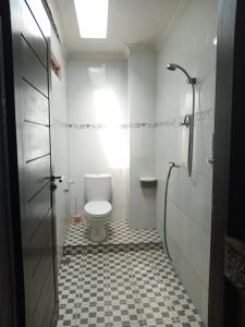 a white bathroom with a toilet and a shower at Homestay Mroom Bali in Perean