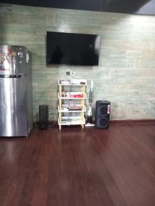 a room with a refrigerator and a tv on a wall at Homestay Mroom Bali in Perean