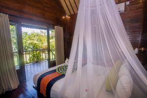 a bedroom with a bed with a mosquito net at Samanta Huts in Nusa Lembongan