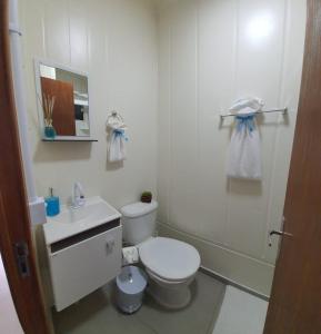 a white bathroom with a toilet and a sink at Blessed Homes in Braço do Norte