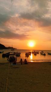 a group of people sitting on the beach watching the sunset at frente al mar Hotel La Morena in Taganga