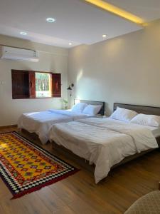 a bedroom with two beds and a rug on the floor at Mabiti hotel in Al-ʿUla