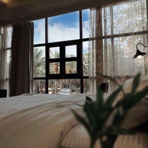 a bedroom with a bed and a large window at Mabiti hotel in Al-ʿUla