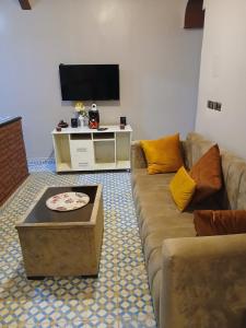 a living room with a couch and a tv at Casa Ayour in Merzouga