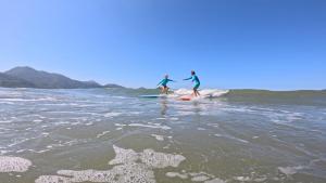 two people are standing on surfboards in the water at Leal Surf School in Rio de Janeiro