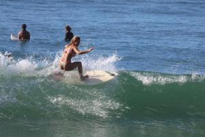 a woman riding a wave on a surfboard in the ocean at Leal Surf School in Rio de Janeiro