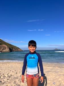 a young boy standing on the beach at Leal Surf School in Rio de Janeiro