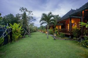 a yard in front of a house with palm trees at Samanta Huts in Nusa Lembongan