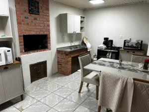 a kitchen with a table and a brick fireplace at Pousada Pampeano in São Gabriel
