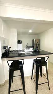 a kitchen with a counter with two black stools at Cabrero Beach 1212 in Cartagena de Indias +17 photos