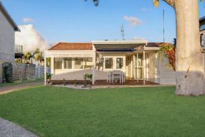 a white house with a table in a yard at Casa Esperanza by Experience Jervis Bay in Vincentia
