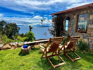 two chairs sitting in the grass in front of a house at Inkapacha ecohostel cabañas in Comunidad Yumani