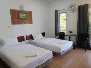 a bedroom with two beds and a table and a window at โรงแรมเพ็ญวิวรีสอร์ท Phenview resort in Amphoe Phen