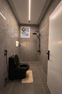 a bathroom with a black toilet and a shower at شقة الخليل in Quai