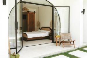 a bedroom with a bed in a glass enclosure at Tyde Bali Boutique Hotel in Uluwatu