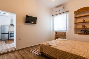 a bedroom with a bed and a television on the wall at Casa de Flores 2 in Plaka Milou