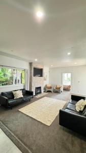 a living room with two black couches and a fireplace at Gosling Grove Hideaway in Turangi