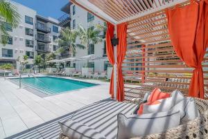 an outdoor patio with a swimming pool and orange umbrellas at Volar Luxurious #328 in Los Angeles
