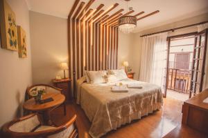 a bedroom with a bed and a table and a window at Pousada das Hortênsias in Campos do Jordão