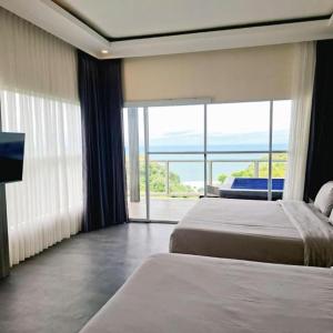 a hotel room with two beds and a large window at Stone Valley Resort & Beach in Tepus
