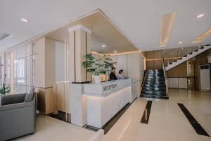 a lobby of a building with two people standing at a counter at Hotel 88 Batulicin by WH in Batulicin