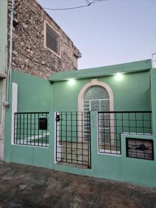 a green house with a gate and a building at Merida Centro House with Private Pool and Air Conditioning in Mérida