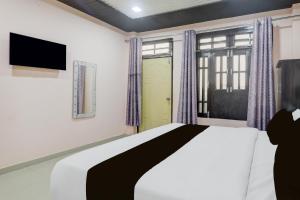 a bedroom with a bed and a tv and a window at Hotel O Shri Buddheshwar Temple Lucknow in Alambagh