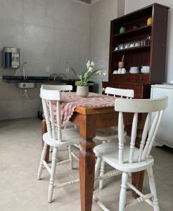 a dining room table with four white chairs and a table at Casa 3 Suites Confortaveis in Chapada dos Guimarães