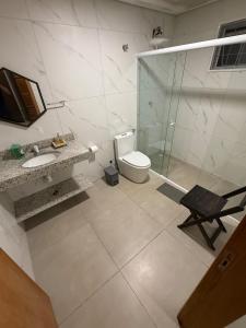 a bathroom with a toilet and a glass shower at Casa 3 Suites Confortaveis in Chapada dos Guimarães