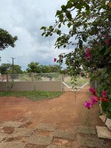 a fence with pink flowers in front of a yard at Casa 3 Suites Confortaveis in Chapada dos Guimarães