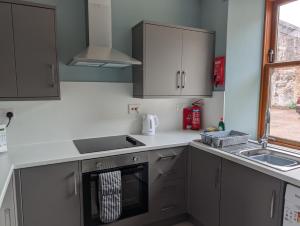 a kitchen with gray cabinets and a sink and a stove at Argyll Place in Campbeltown
