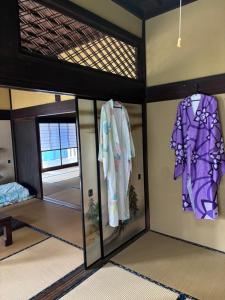 a room with glass doors and clothes hanging on the wall at Edo house in Shiigi