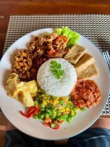 a plate of food with rice and vegetables on a table at The Beachbreaks Medewi in Airsatang