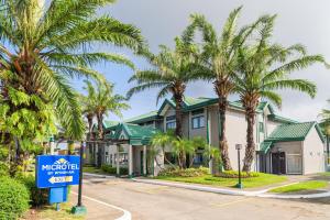 a sign in front of a house with palm trees at Microtel by Wyndham Cabanatuan in Cabanatuan