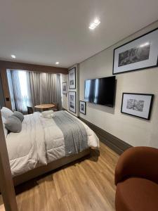 a bedroom with a bed and a flat screen tv at Loft de Luxo com Charme e Design Moderno in Cuiabá
