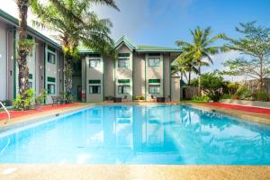 a swimming pool in front of a house with palm trees at Microtel by Wyndham Cabanatuan in Cabanatuan