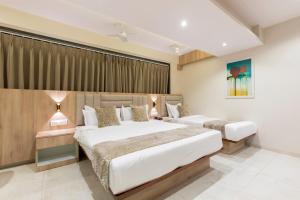 two beds in a hotel room with curtains at Hotel Kurla Suites in Mumbai