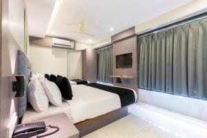 a hotel room with a bed and a television at Hotel Kurla Suites in Mumbai