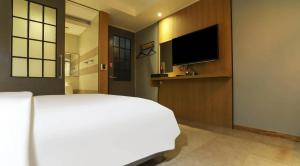 a bedroom with a white bed and a flat screen tv at 호텔 페르소나 in P'ungnyŏn-gol +20 photos