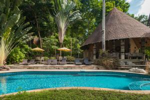a pool at a resort with chairs and umbrellas at Tolani Resort Koh Kood in Ko Kood