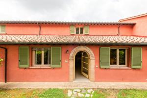 a red house with green shutters and a door at Historic Farmhouse Between Two Tuscan Valleys in Trequanda